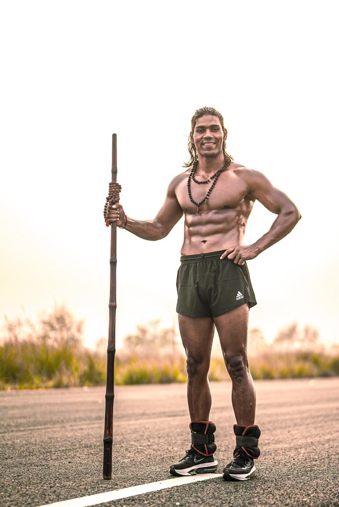 Raja Yadav smiling with a bamboo staff
